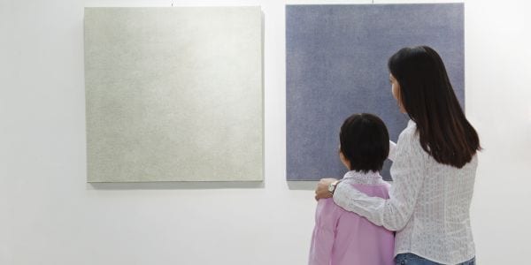 Mother and daughter looking at painting in an art gallery