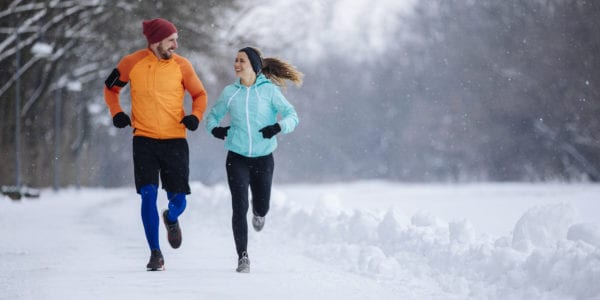 Male and female running outdoors in a beautiful snowy surroundings