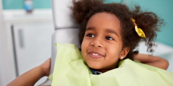 Portrait of satisfied child in dental chair after successful dental treatment