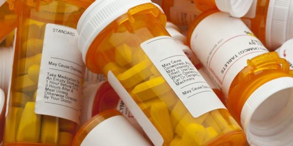 a pile of prescription bottles filled with white pills
