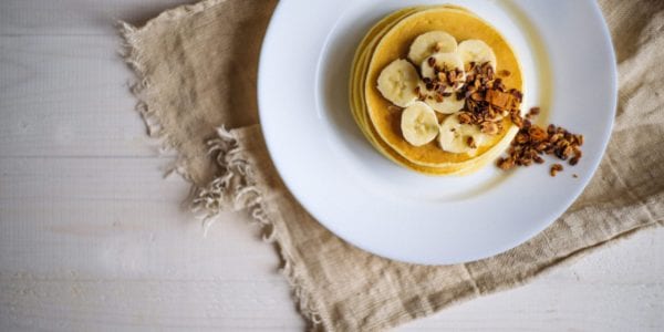 pancakes on a plate with bananas and granola
