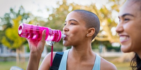 Women smiling and drinking a water bottle outside