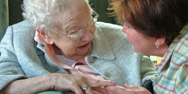 elderly woman holding adult woman's hands