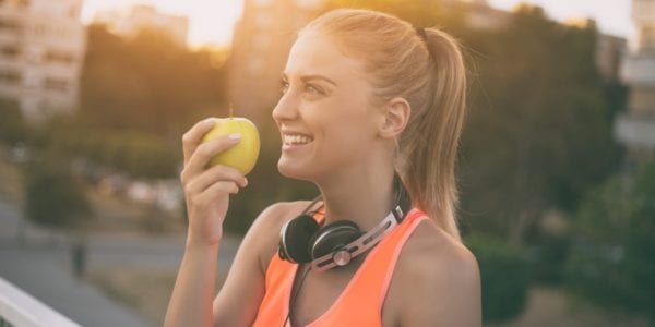Woman in workout clothes eating apple