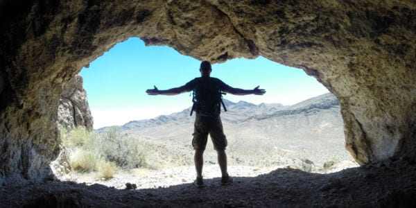 man standing in a cave with a backpack