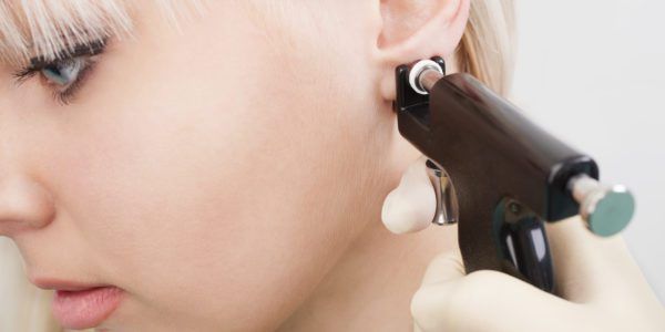 Woman having ears pierced with ear piercing gun