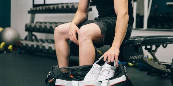 A man puts gym shoes into his bag after a workout