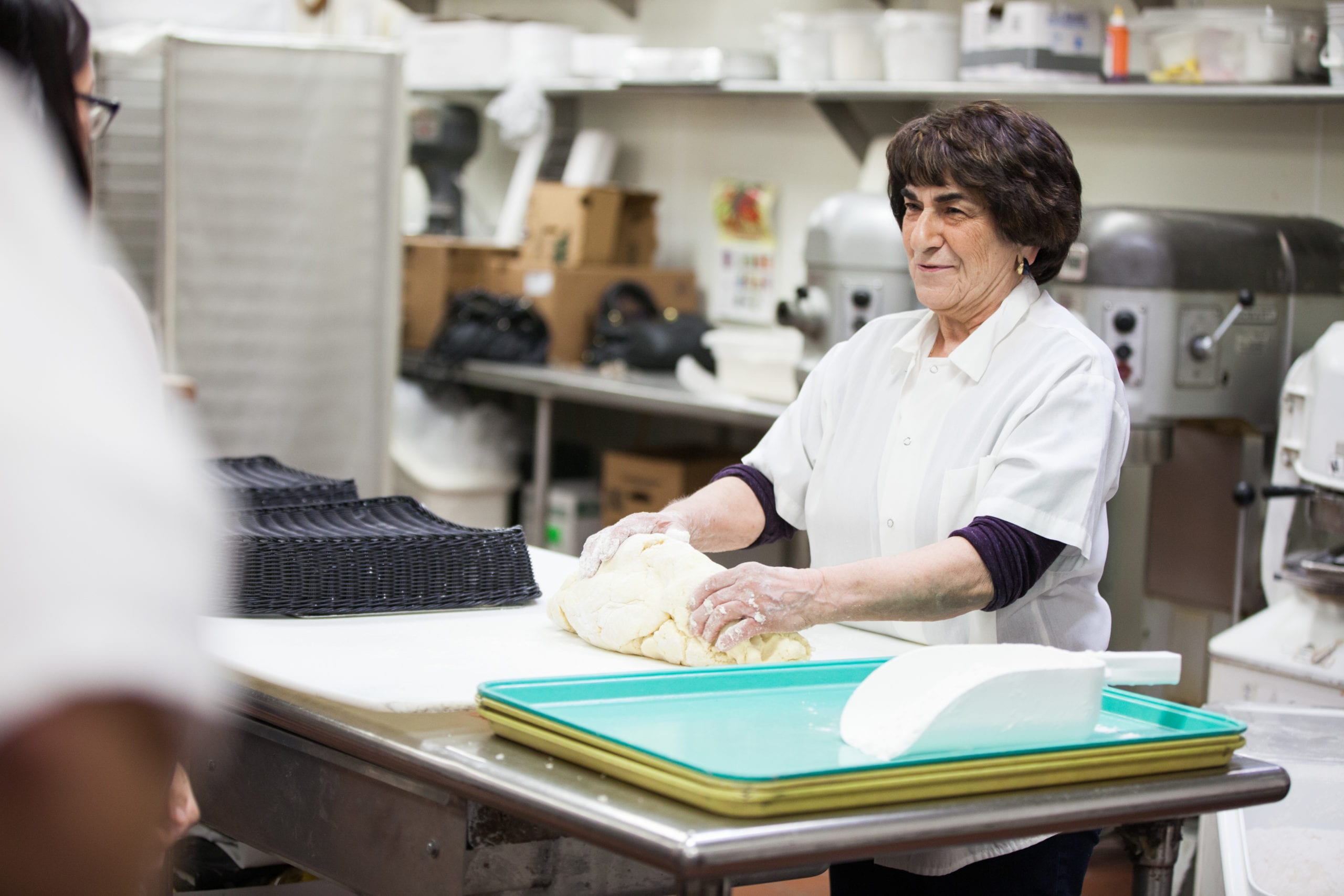 A woman standing at a table rolling dough