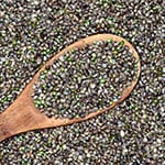 a wooden spoon filled with and surrounded by hemp seeds