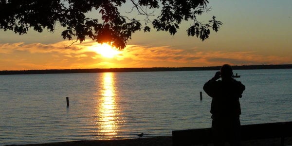 A man watches the sunset on a lake