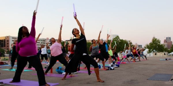 Men and women doing moonlight yoga with glow sticks