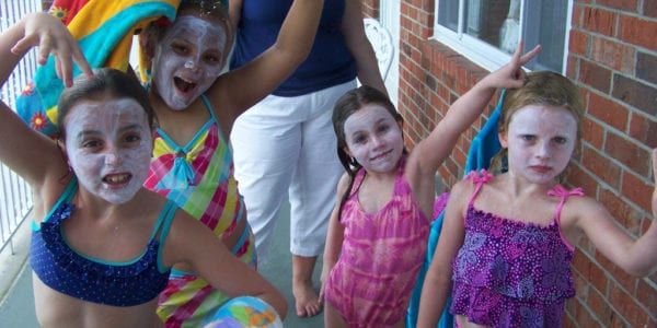 Young girls by the pool with sunscreen on their faces.