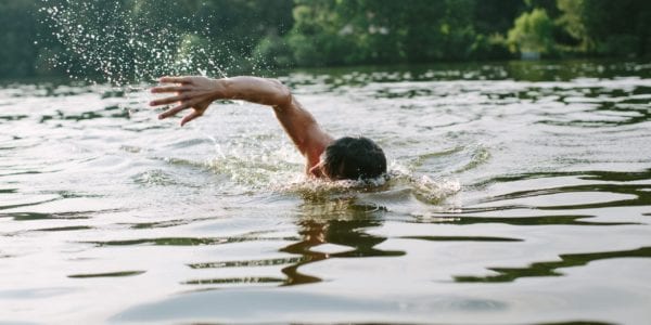 man swimming in lake