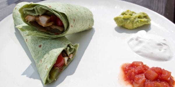 Roll-up on a plate with salsa, sour cream and guacamole.