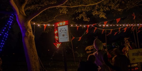 night time scene with string lights and a red arrow with a sign attached to it.