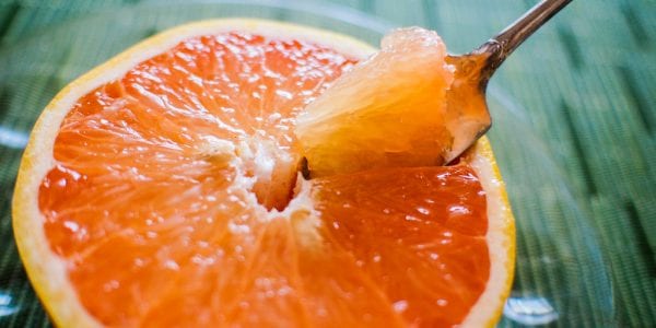 a spoon slicing into half a grapefruit.