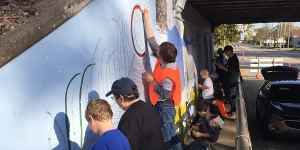 Volunteers paint a freeway overpass