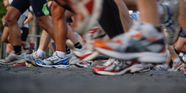 Image captures runners in motion from a perspective of their lower legs and feet.