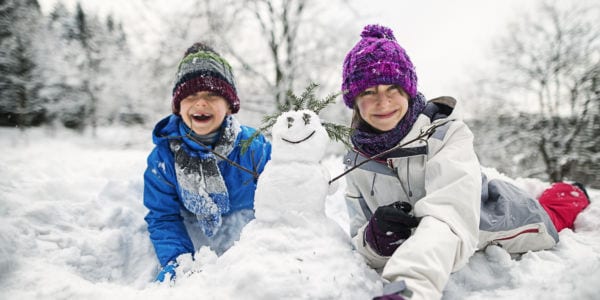 Kids making a snowman in the snow.