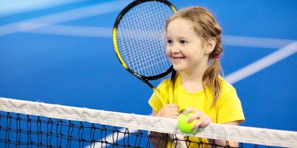 Little girl playing tennis on an indoor court.