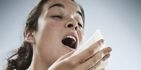 Woman sneezing due to seasonal allergies