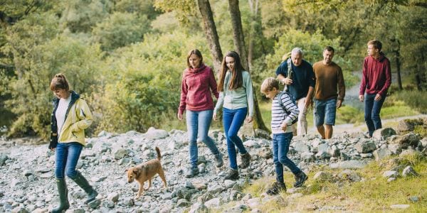 Family hiking together through a park with their pet dog.