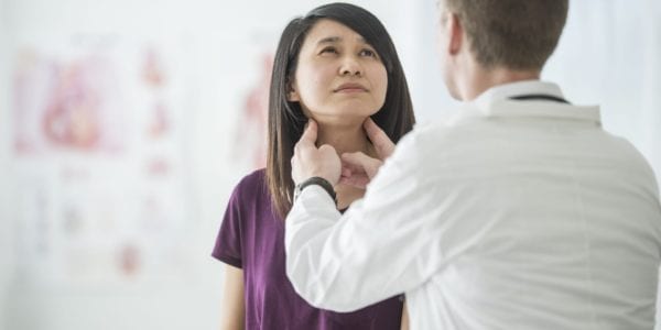 A woman is at the doctor's office for a thyroid exam