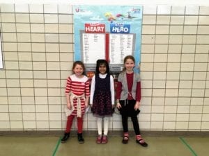 Three students pose in front of a poster at school