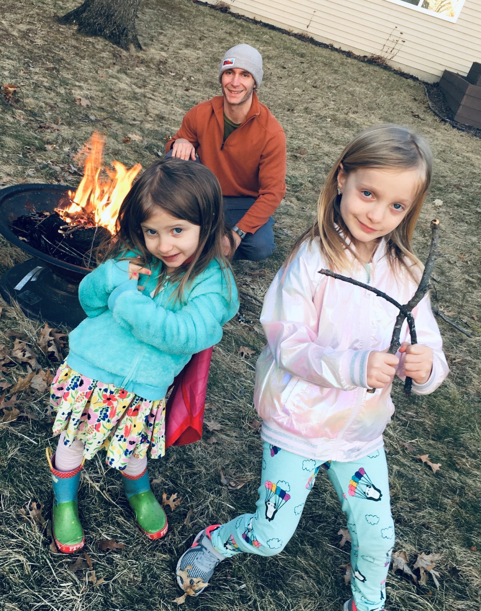 Two girls around the campfire with their dad