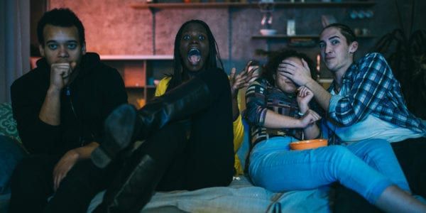 Young adults reacting to a scary movie scene