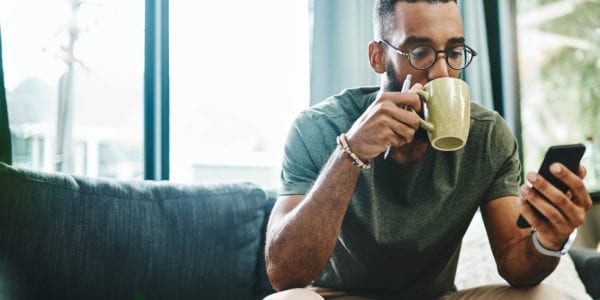 Man drinking coffee while using social media