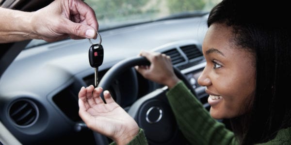 Young African American woman eagerly takes car key handed to her