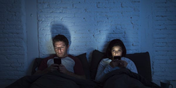 Couple looking at their phones in bed