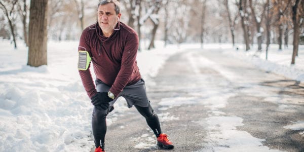 One man, senior adult guy preparing for jogging outdoors in park, on a cold winter day alone.
