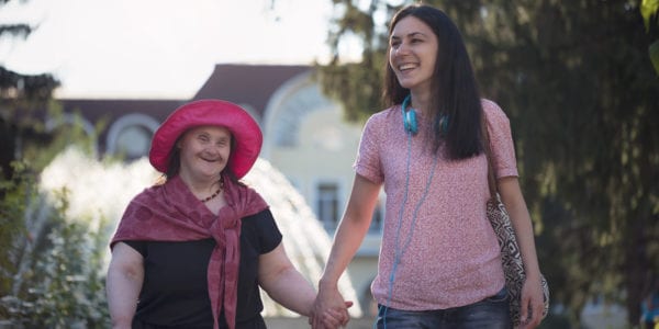 Woman with Down Syndrome and her friend walking in a park