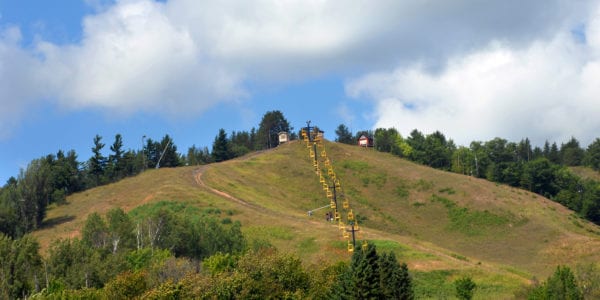 Michigan Tech ski lift is surrounded by summer. Yellow ski lift chairs descend to bottom of Quincy Hill in Upper Peninsula, Michigan.