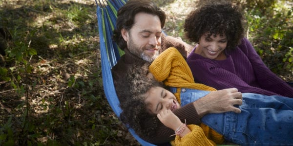 Family lying and playing on a hammock in the woods