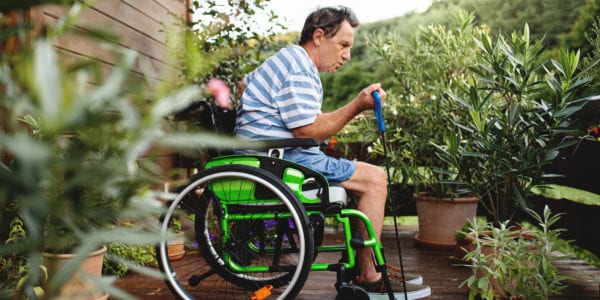 Senior man in wheelchair doing exercise on terrace.