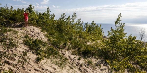 A young woman hikes on sand dunes on the coast of Lake Michigan