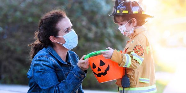 Caucasian Mature woman and a child boy wearing protective face masks before going to ask trick or treat halloween