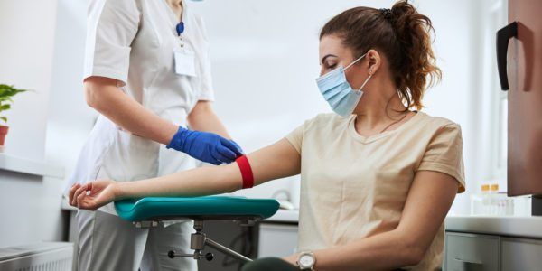 Experienced phlebotomist preparing a woman for blood draw