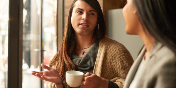 Gender fluid individual speaks with a friend at a coffee shop about setting boundaries as a form of self-care