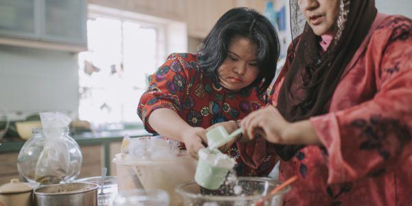 malaysian mother and her down syndrome daughter making traditional malay dessert in kitchen
