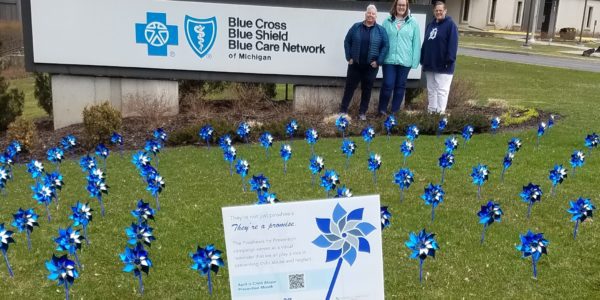 BCN Cascade Grand Rapids - employees stand next to a pinwheel garden in the grass in front of the office for Child Abuse Prevention month