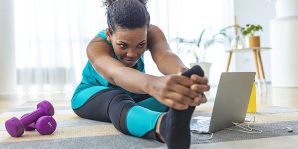 Woman stretches her legs in front of her laptop