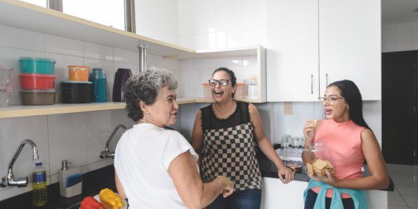 Grandmother, mother and daughter chatting while prepare food in the kitchen