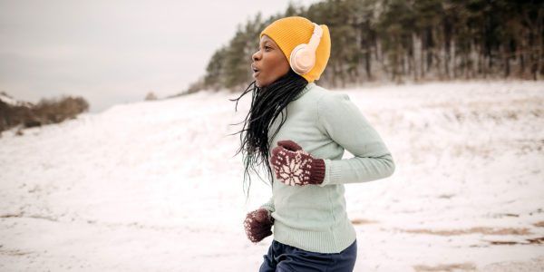 A young Black woman runs outdoors during the winter.