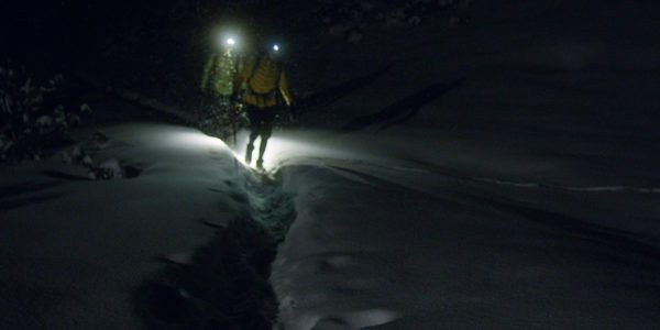 Winter mountain adventure. Young couple on a trail. Night blizzard