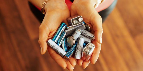 Closeup on different types of batteries in a woman's hand.