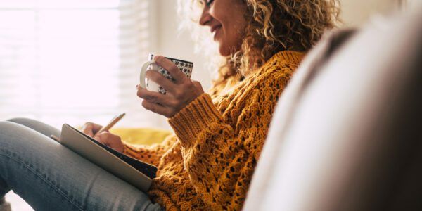 Woman sits at home with coffee and a journal